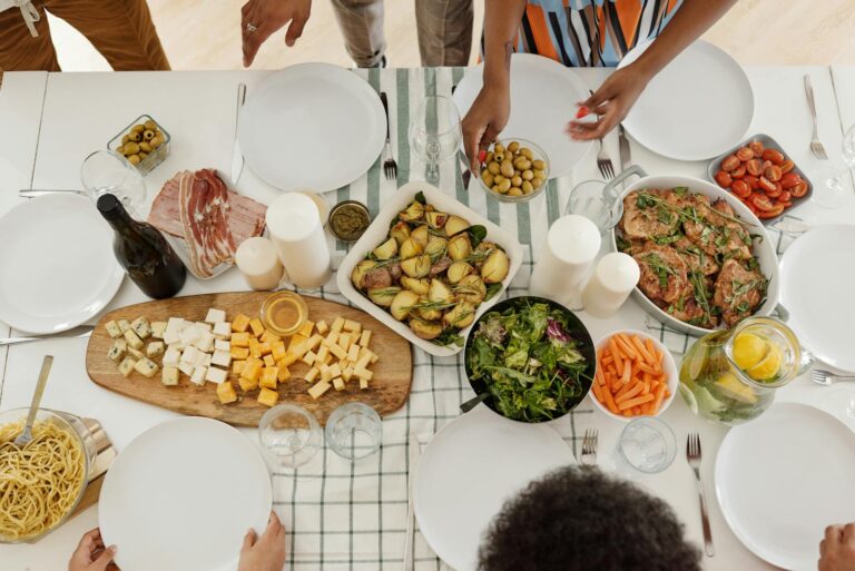 Overhead view of a family gathering with a variety of foods on a dining table.