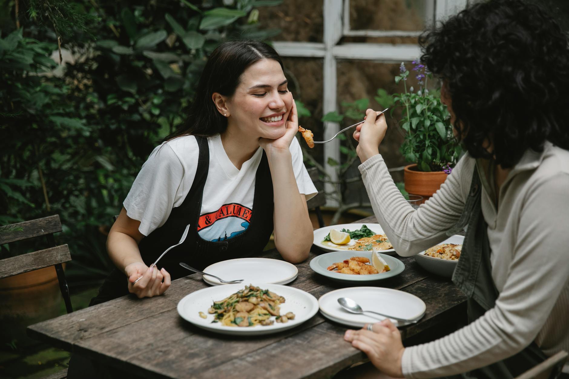 woman feeding girlfriend with fried seafood in garden