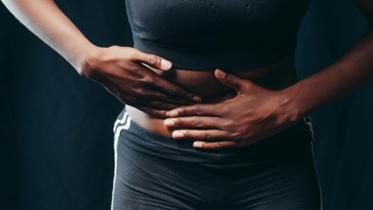 person wearing black active wear holding her tummy