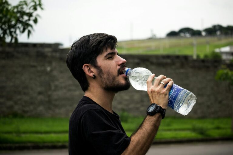 man wearing black shirt drinking water